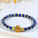 Lapis lazuli Om Mani Padme Hum bracelet with gold metal spacers and enamel mantra charm displayed on white book background