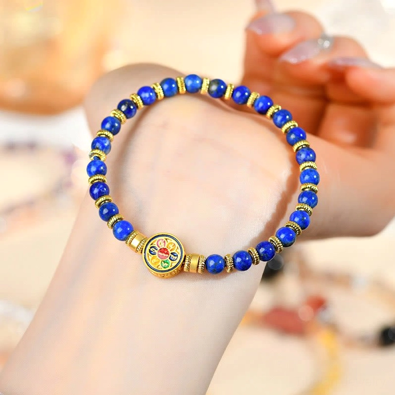 Lapis lazuli beaded bracelet held in hand showing neat bead layout and enamel Om Mani mantra charm