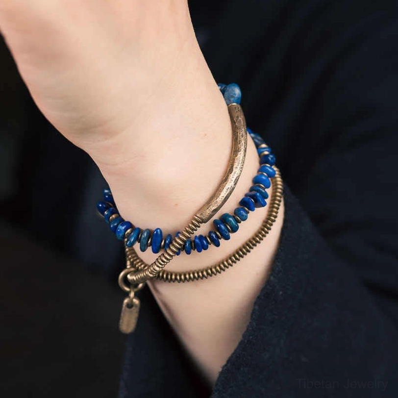 On-wrist styling photo showing lapis lazuli triple wrap bracelet worn on human wrist with dark clothing background