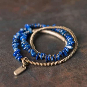 Lapis Lazuli triple wrap bracelet with copper beads and brass tube, top-down side angle view on dark matte desktop