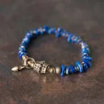 Lapis lazuli vintage bracelet with irregular blue chips and aged bronze toggle clasp, high side view on textured background