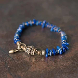 Lapis lazuli vintage bracelet with irregular blue chips and aged bronze toggle clasp, high side view on textured background