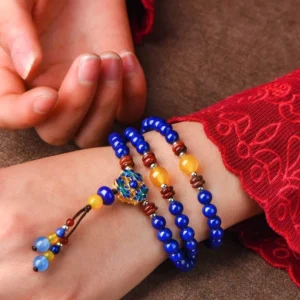 Handmade Lapis Lazuli and Yellow Agate spiritual bracelet worn on wrist with red embroidered Tibetan clothing