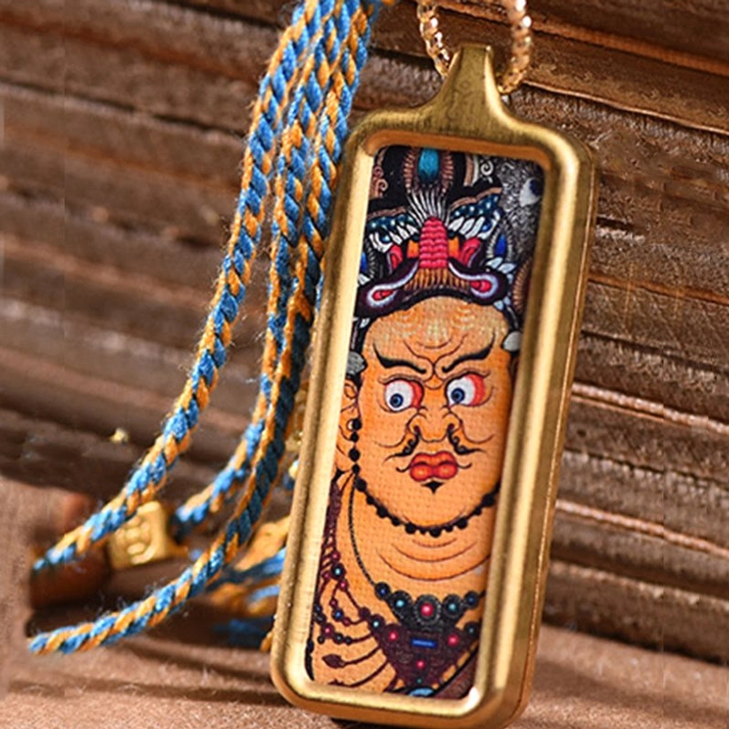 Large Tibetan wealth deity thangka pendant close-up with gold frame and blue-yellow lanyard
