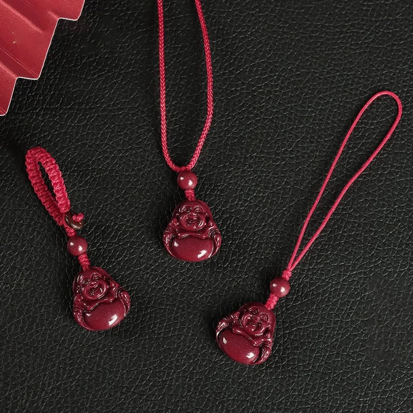 Close-up detail of carved Laughing Buddha cinnabar charm with decorative red bead and woven rope