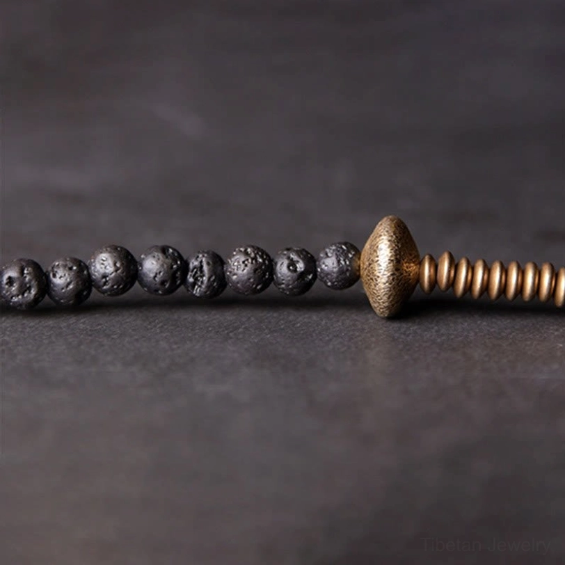Black lava rock beads with brass copper focal point close-up flat lay