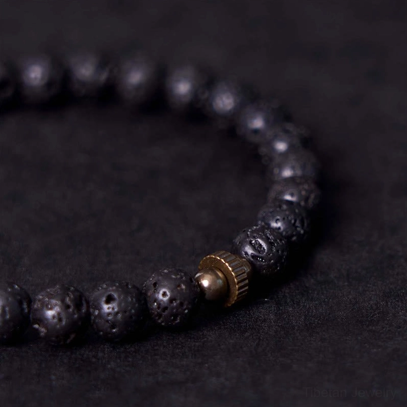 Extreme close-up of lava rock beads showing porous volcanic texture and brass metal spacers, grounding stone detail