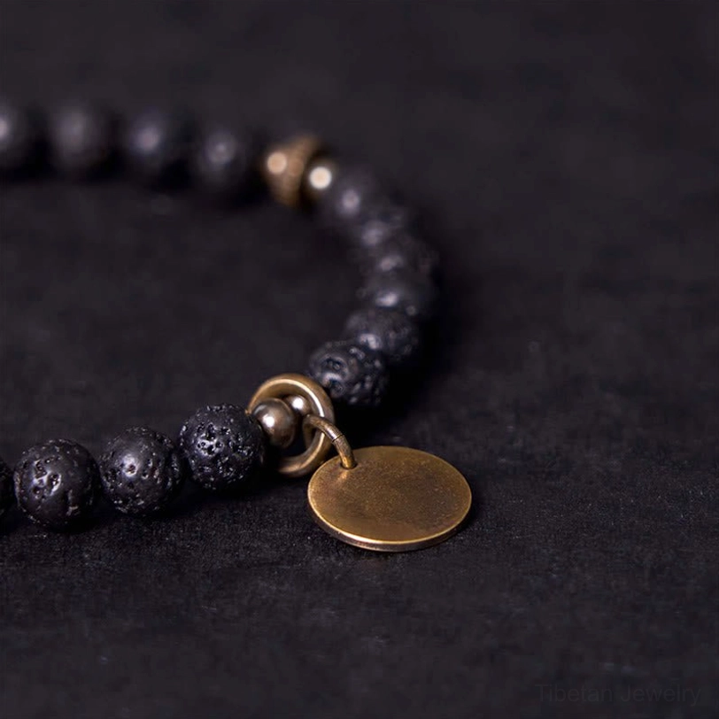 Close-up side view of lava rock stress relief bracelet highlighting bronze clasp and round copper charm