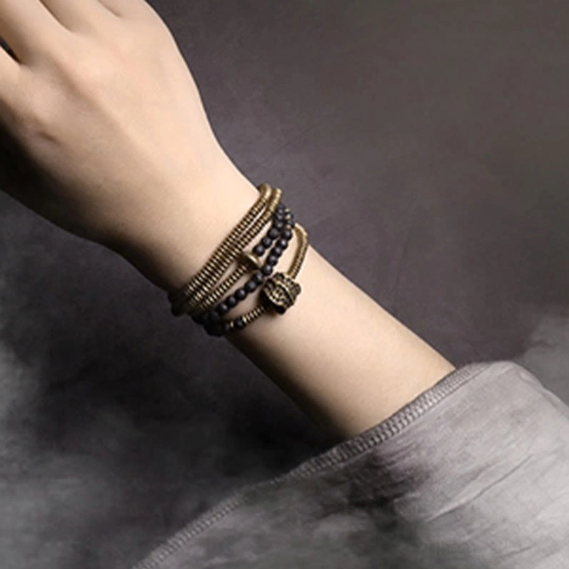 Multilayered lava rock bracelet with brass wrapped bands and metal clasp detail