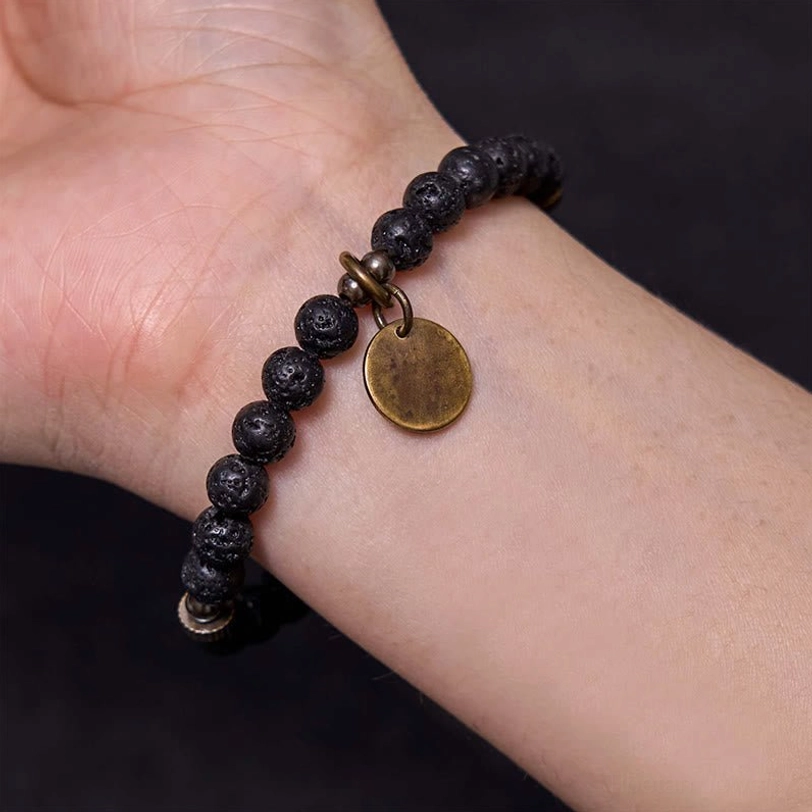 Close-up inner wrist view of lava rock healing bracelet showing charm spacing and comfortable skin contact