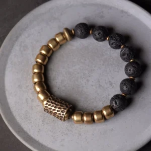 Black lava rock beads with bronze brass spacers on ceramic plate, minimalist wellness jewelry