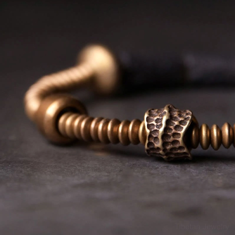 Close-up side view of lava rock and polished copper bead detail showing texture and hammered metal work
