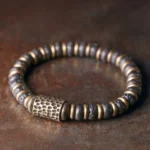Vintage handcrafted lava rock copper bracelet with hammered brass accents, flat lay top-down view on textured surface