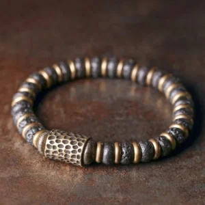 Vintage handcrafted lava rock copper bracelet with hammered brass accents, flat lay top-down view on textured surface