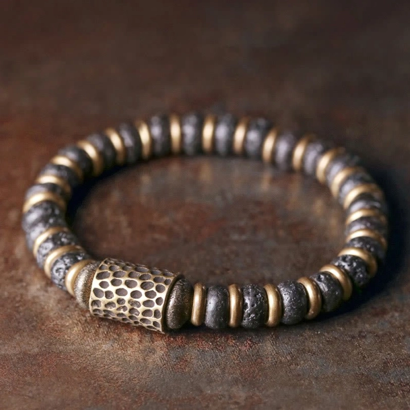 Vintage handcrafted lava rock copper bracelet with hammered brass accents, flat lay top-down view on textured surface