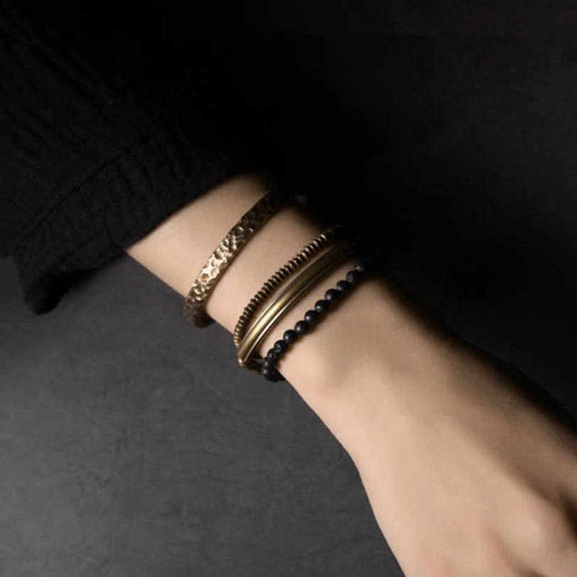 Side view of grounding lava rock beaded bracelet with embossed antique copper tube worn on wrist
