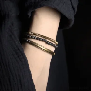 Layered vintage copper and lava rock bracelet stack worn on wrist showing grounding jewelry in close-up detail