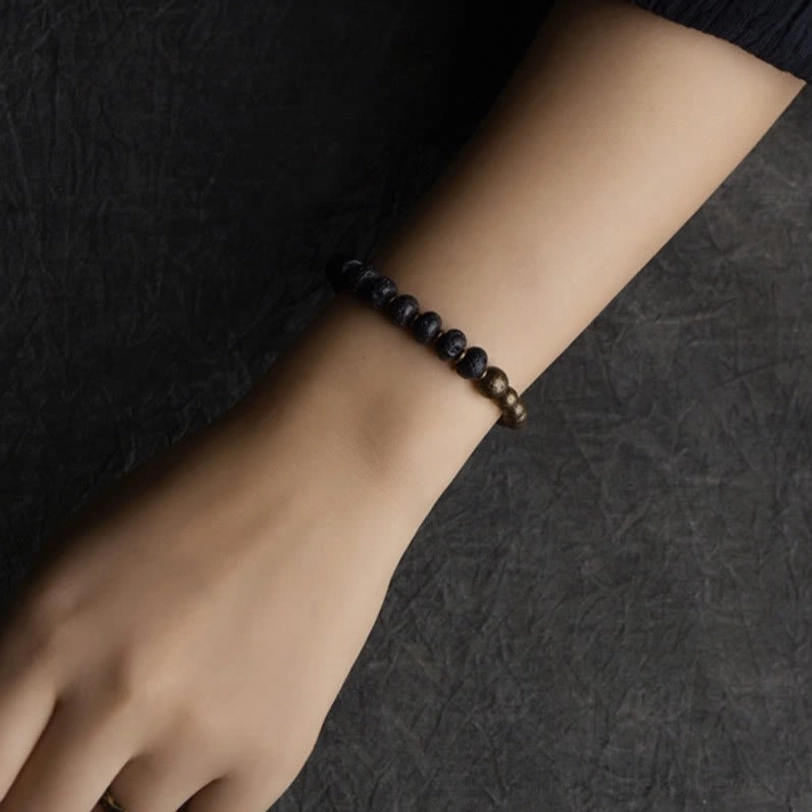 Lava rock copper bracelet worn on wrist showing minimalist design with small black stone beads and bronze accents