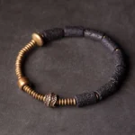 Lava rock copper wealth bracelet flat lay top view with black cylindrical beads and antique copper accents on dark background