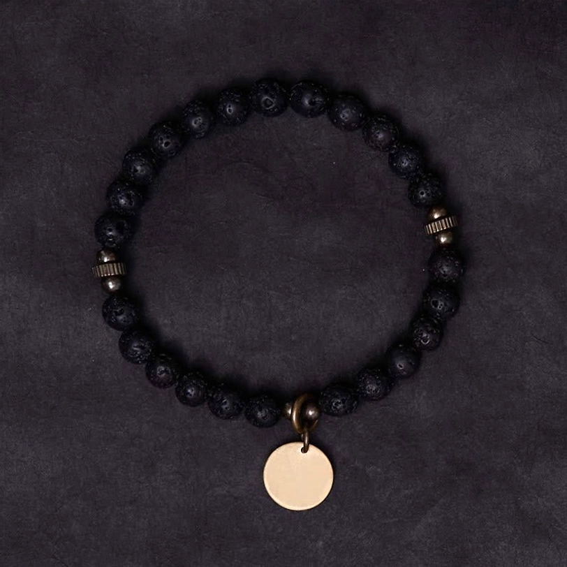Full circle view of lava rock grounding bracelet with copper charm and elastic band, demonstrating complete design from above