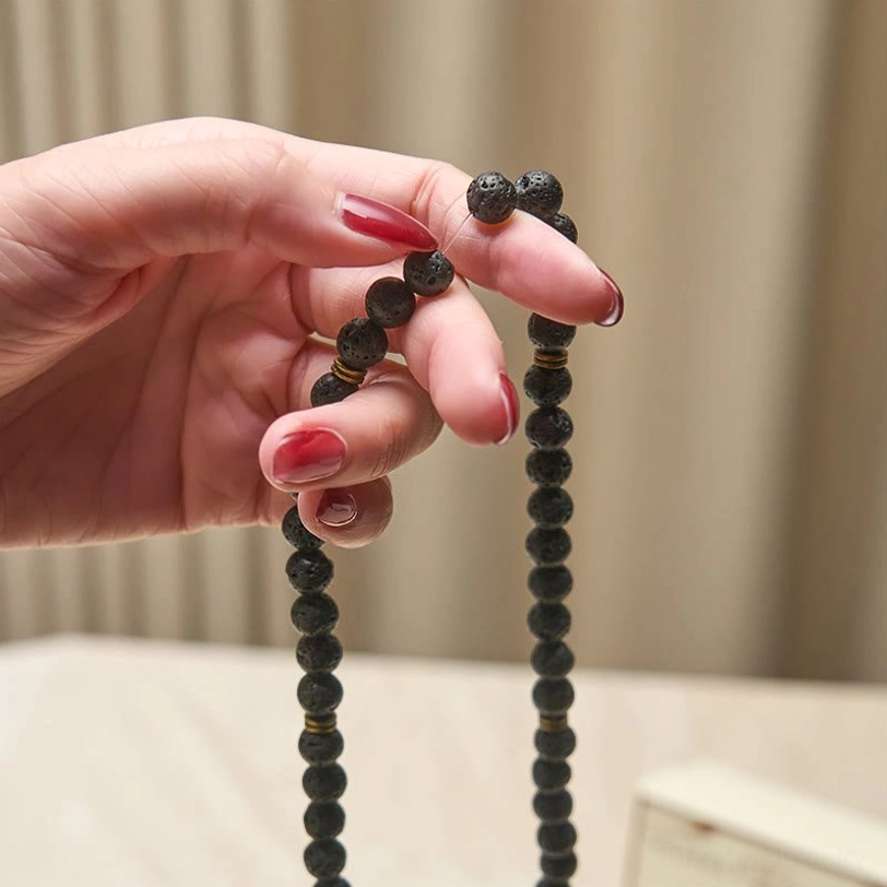 Held lava rock mala beads showing detached bead segments and porous texture in natural lighting