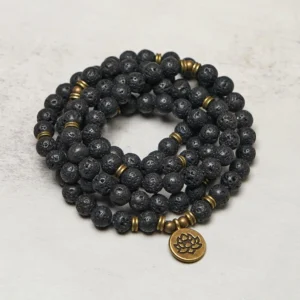 Coiled lava rock mala necklace flat lay displaying stacked bead strands with bronze lotus charm and metal spacer beads