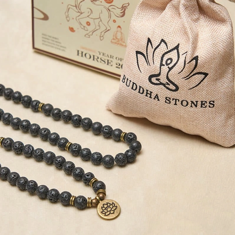 Lava rock mala sets display with multiple strands, bronze lotus charm and branded storage pouch on beige surface