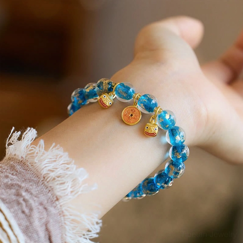 Light blue liuli glass fortune bracelet with gold Pi Xiu charm and lucky coin pendant detail