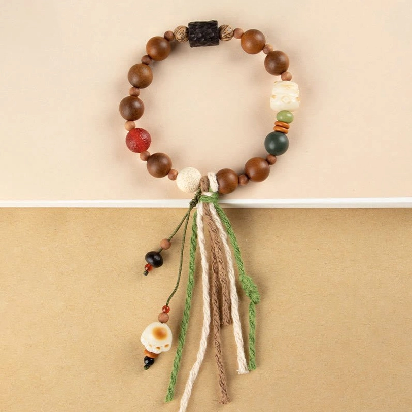 Handcrafted lightning strike wood tassel bracelet with mixed color beads and cat paw charm, flat lay on beige tabletop showing complete design