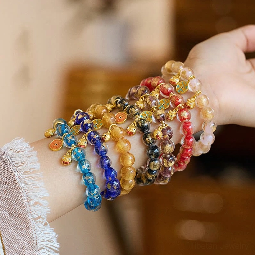 Assorted color liuli glass fortune bracelets with Pi Xiu metal charms, worn on wrist from side perspective