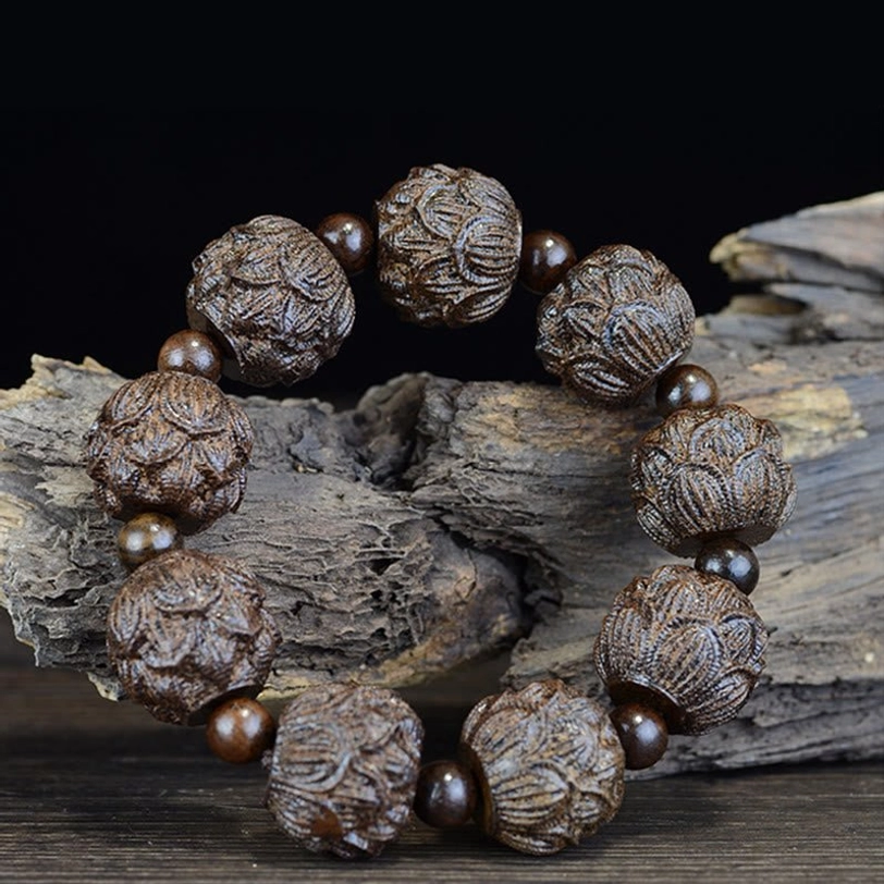 Full lotus engraved ebony wood bracelet overhead view with natural wood grain texture on dark surface