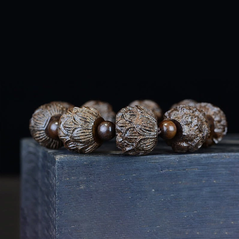 Lotus engraved ebony wood bracelet low angle side view showing carved lotus patterns and smooth wood finish