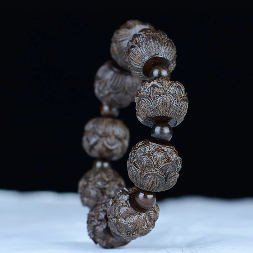 Ebony wood lotus carved bracelet vertical display on white fabric background showing bead arrangement