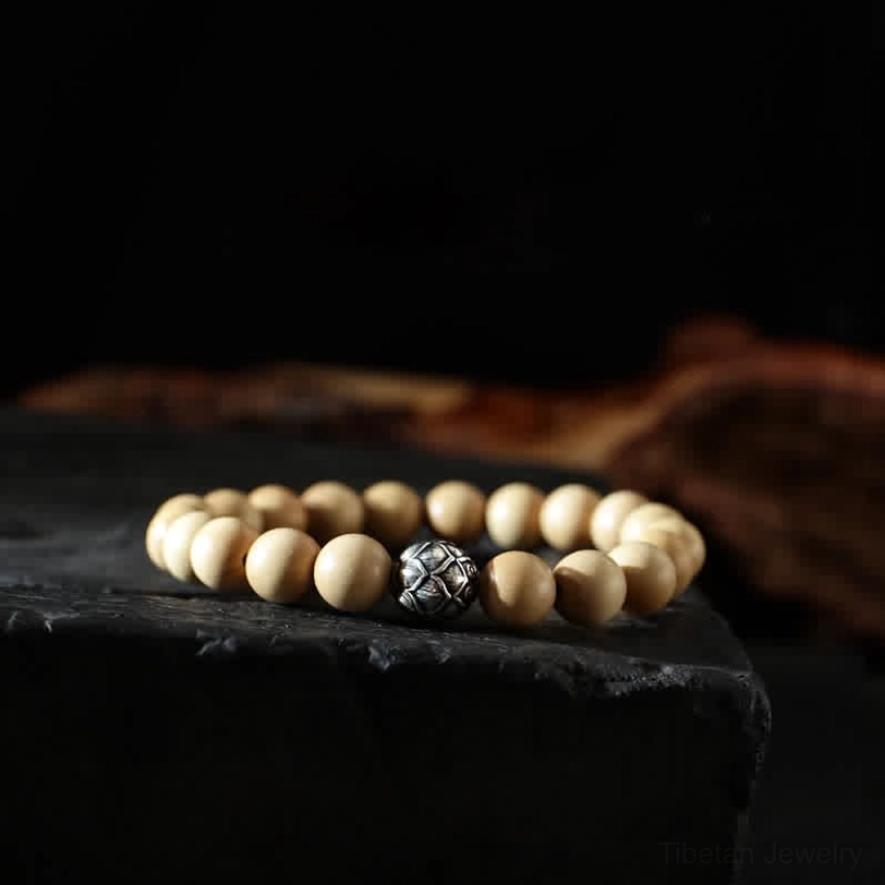 Wooden bracelet with lotus engraved silver spacer bead - top-down flat lay on dark background