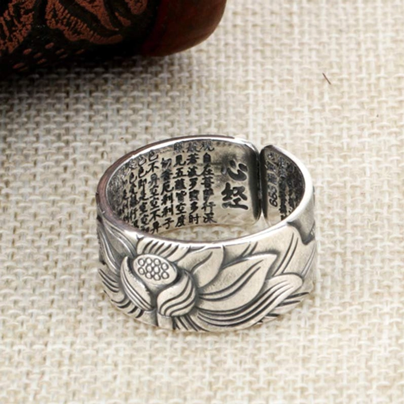 Tibetan-inspired lotus heart sutra silver ring with clear Heart Sutra Sanskrit characters engraved on inner surface, top view on linen fabric