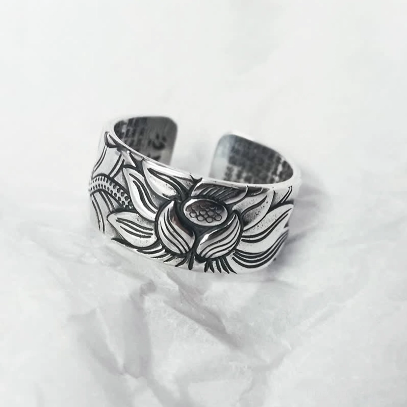 999 Sterling Silver Lotus Heart Sutra open adjustable ring with embossed lotus flower pattern, front oblique view on white fabric background
