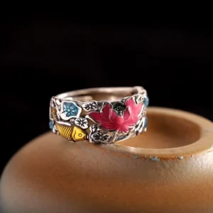 Top oblique view of lotus koi fish silver ring displaying carved flower and fish patterns on ceramic surface