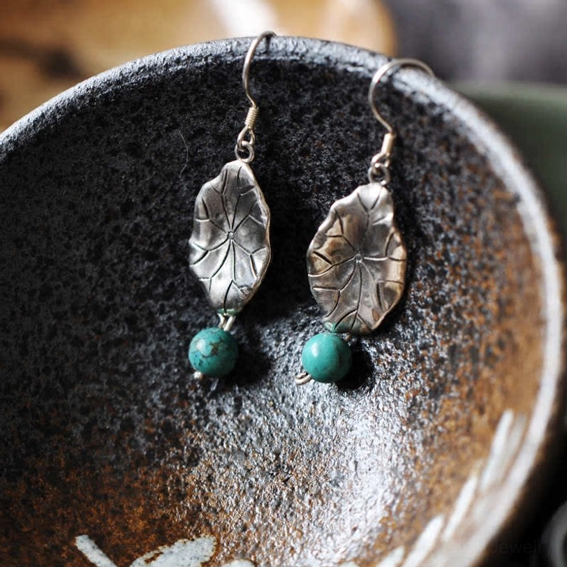 Front close-up of two-tone lotus leaf drop earrings in silver and bronze with turquoise bead details
