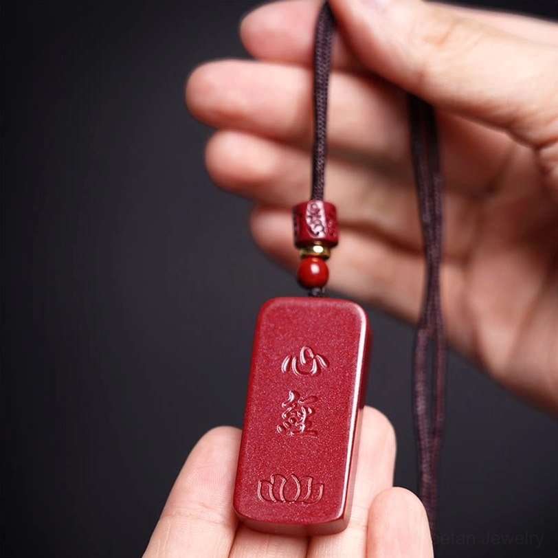 Lotus Heart Sutra cinnabar necklace showing detailed hand-carved Sanskrit characters on matte red cinnabar stone