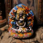 Mahakala wealth Buddha Tibetan clay hand-painted sculpture with gilded accents and lotus pedestal, front view on antique tabletop