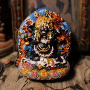 Mahakala wealth Buddha Tibetan clay hand-painted sculpture with gilded accents and lotus pedestal, front view on antique tabletop