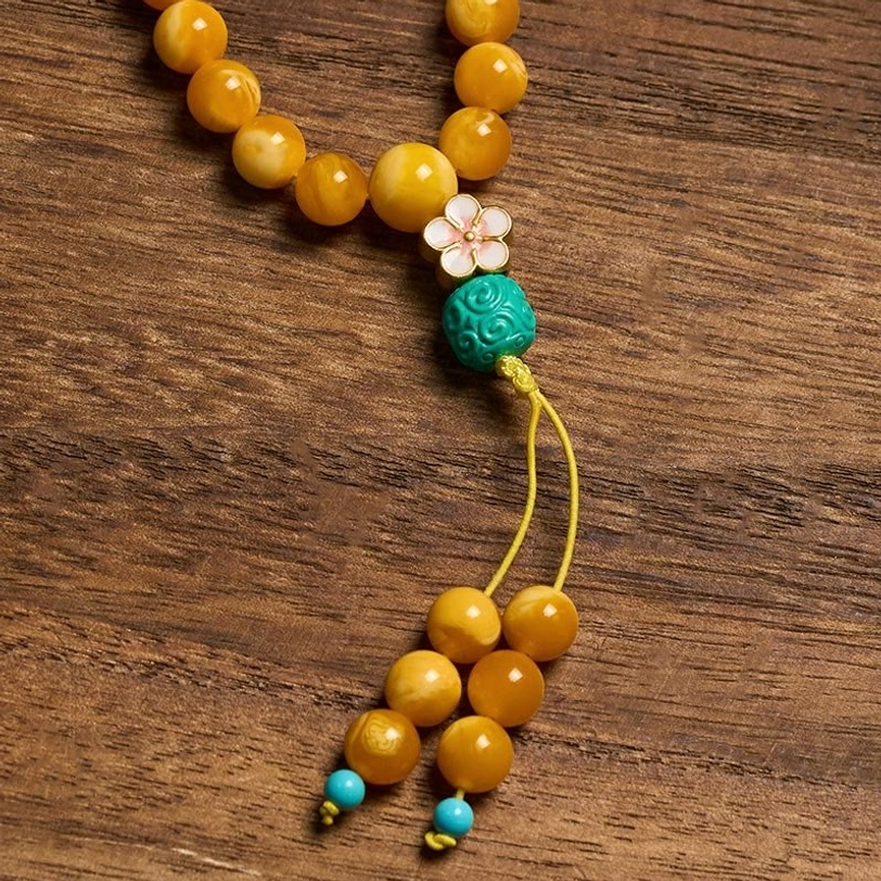 Individual carved turquoise bead and flower charm accent details of the mala with polished amber beads and decorative tassel