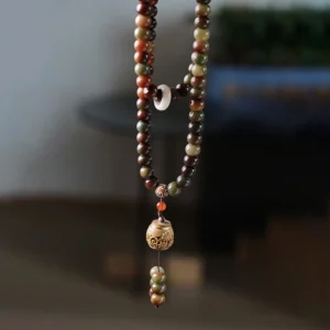 Full 108-bead Tibetan mala necklace with carved dzi accent bead and wooden prayer pendant in flat lay view