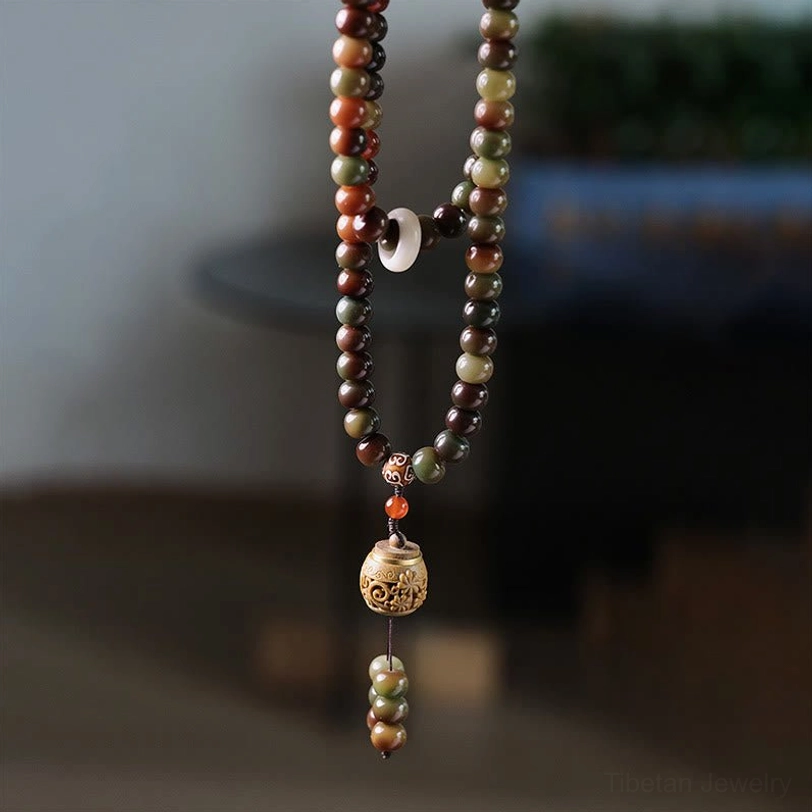 Full 108-bead Tibetan mala necklace with carved dzi accent bead and wooden prayer pendant in flat lay view