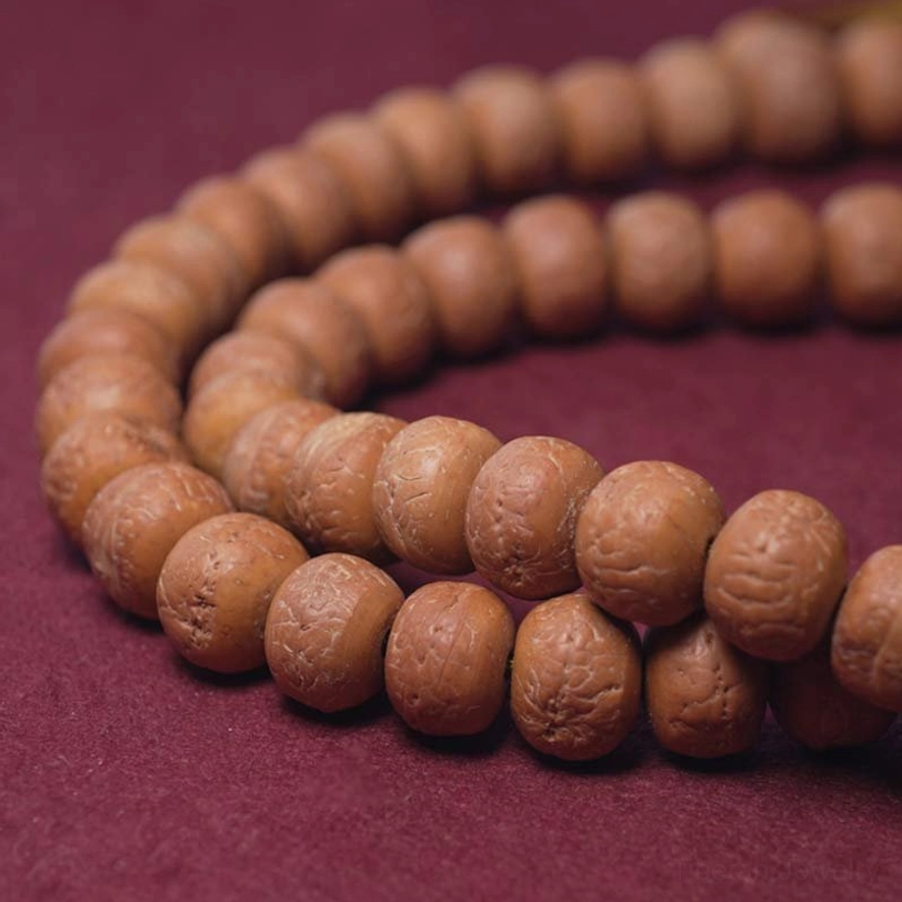 Mala beads close-up flat lay on red fabric showing smooth bodhi seed beads and metal spacer rings