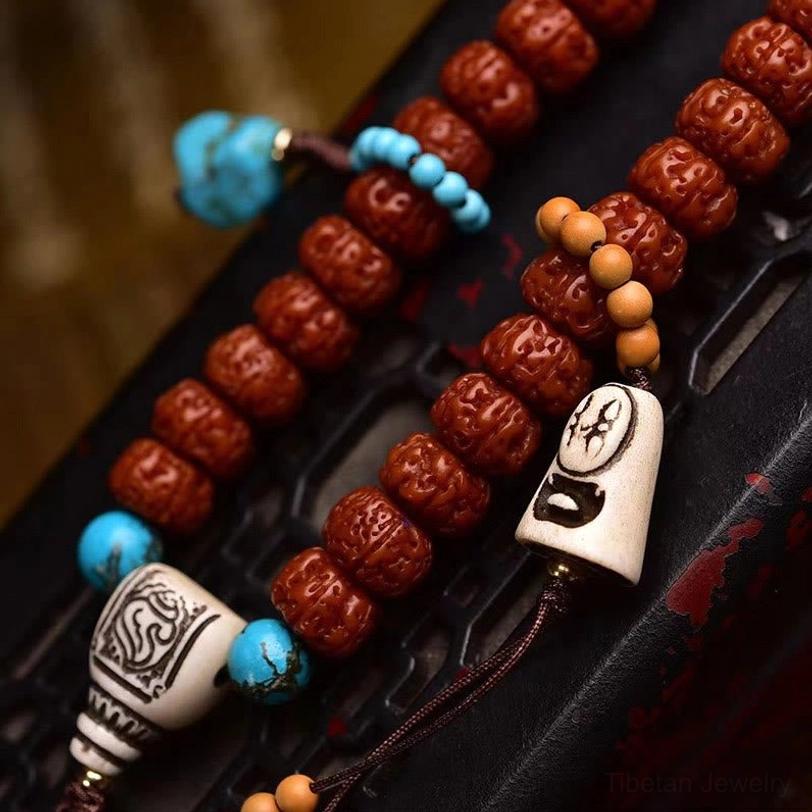 Close-up detail of 108 Bodhi seed mala showing carved rudraksha beads, turquoise and bone accessories, and carved bone pendant