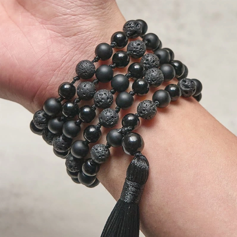 Tibetan mala beads worn as multi-wrap bracelet on wrist showing mixed onyx and porous lava rock texture