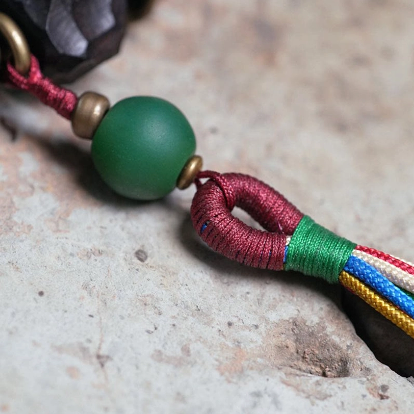 Green accent bead with silk knot and multi-color tassel ends macro photograph