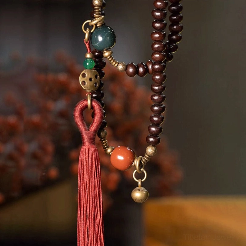 Detailed close-up of purple bodhi mala with metal bell and red tassel decoration