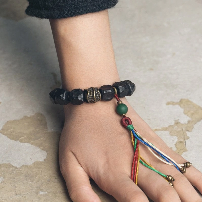 Tibetan mala bracelet on hand with green accent bead and colorful tassel visible